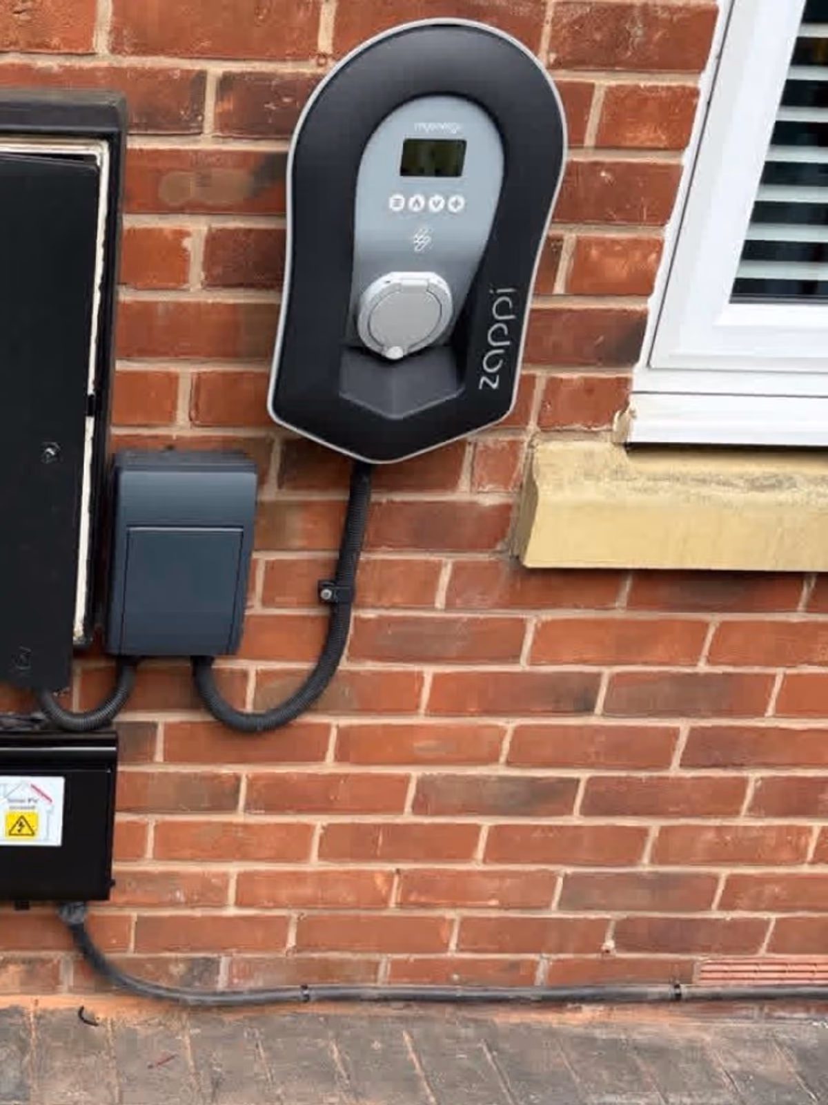 An Zappi EV charger with neatly dressed cabling on brick